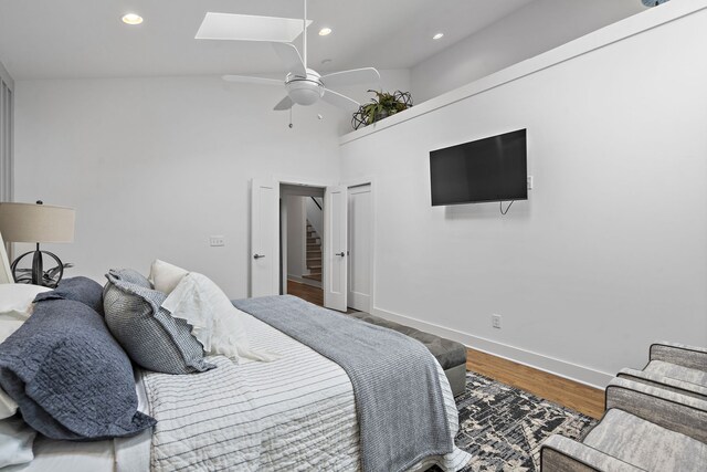 bedroom featuring high vaulted ceiling, hardwood / wood-style floors, a skylight, and ceiling fan