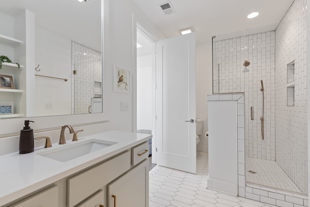 bathroom with a shower with door, vanity, and toilet