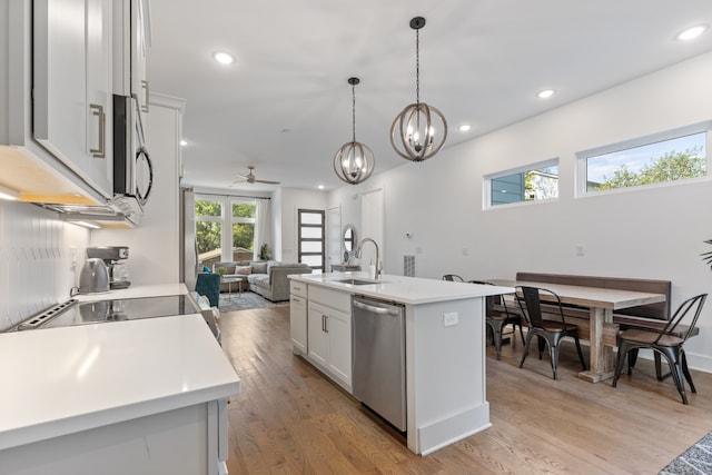 kitchen with a kitchen island with sink, light hardwood / wood-style flooring, sink, ceiling fan, and appliances with stainless steel finishes