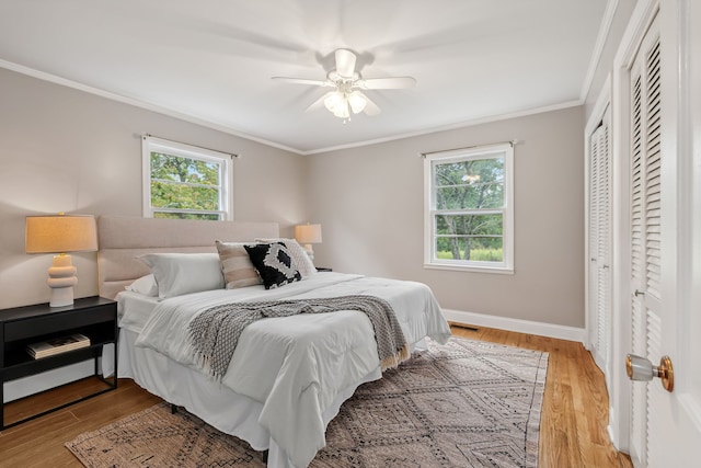 bedroom with ceiling fan, wood-type flooring, and multiple windows