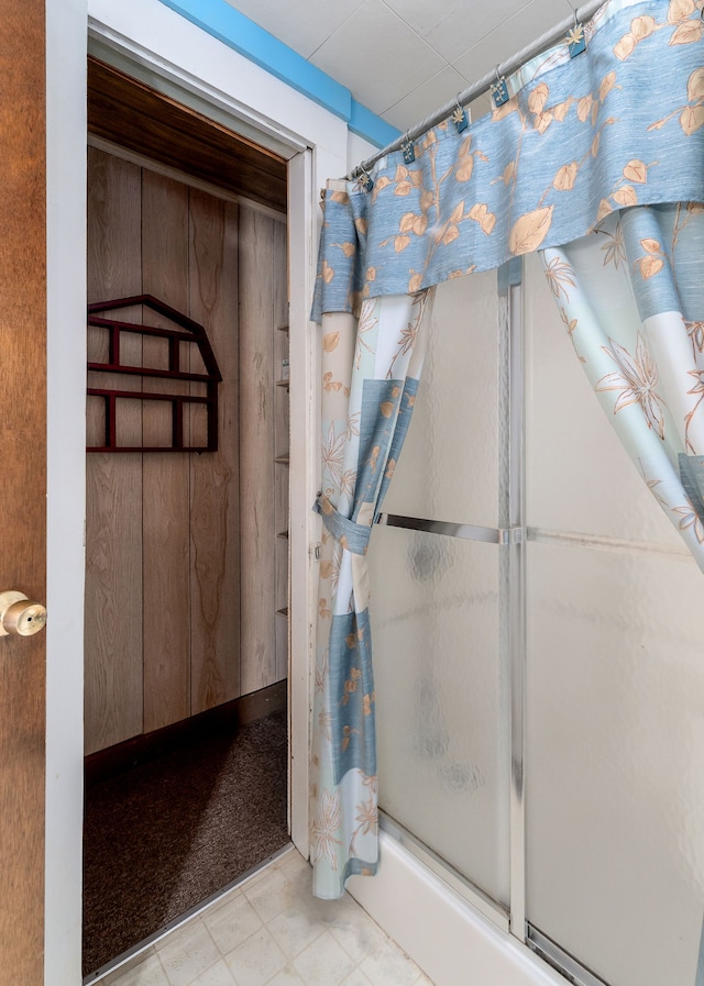 bathroom featuring wood walls and walk in shower