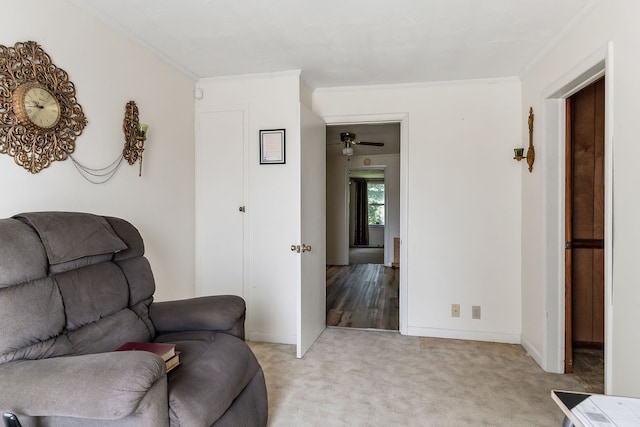 living area with light colored carpet, ceiling fan, and ornamental molding