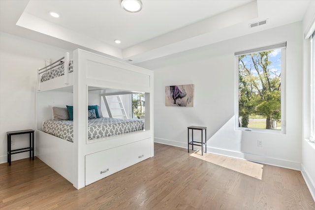 bedroom with a raised ceiling and wood-type flooring