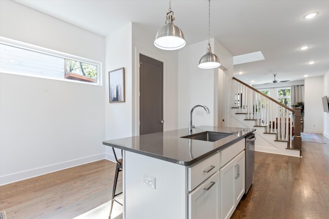 kitchen featuring a wealth of natural light, hardwood / wood-style flooring, a center island with sink, and white cabinetry