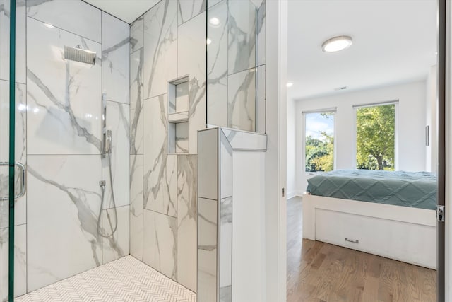 bathroom featuring wood-type flooring and a tile shower