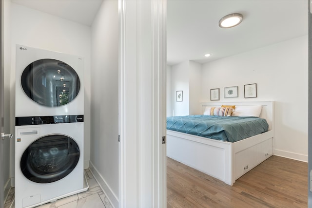 washroom with stacked washer and clothes dryer and light hardwood / wood-style flooring