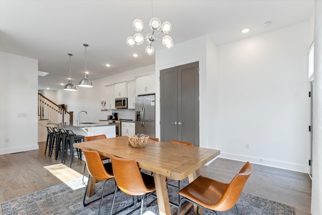 dining space with dark wood-type flooring, sink, and an inviting chandelier