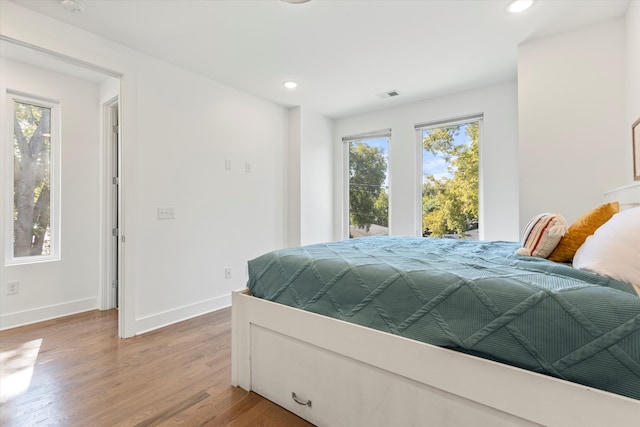 bedroom with wood-type flooring and multiple windows