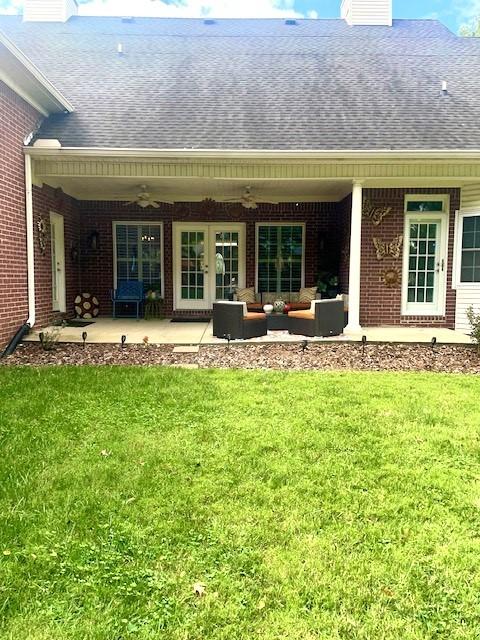 rear view of house featuring a patio area, a yard, outdoor lounge area, brick siding, and roof with shingles