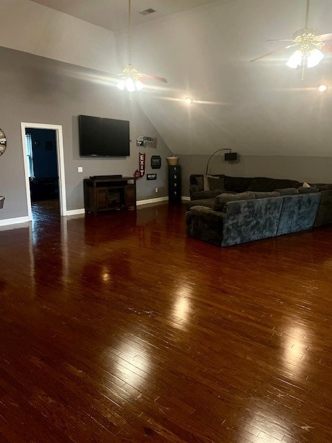 living room featuring dark wood-type flooring, ceiling fan, vaulted ceiling, and a fireplace