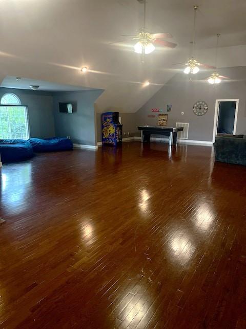 unfurnished living room with baseboards, hardwood / wood-style flooring, a ceiling fan, and lofted ceiling