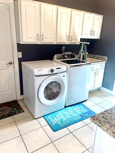 clothes washing area with washing machine and dryer, a sink, cabinet space, and light tile patterned floors