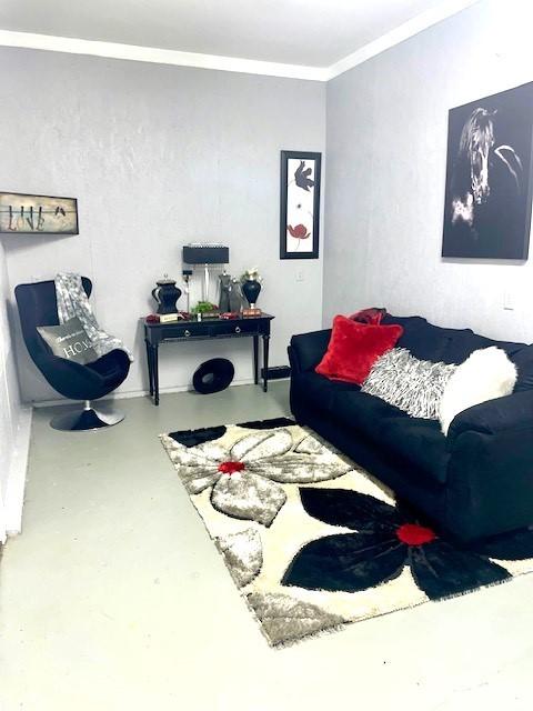 living area with finished concrete flooring and ornamental molding