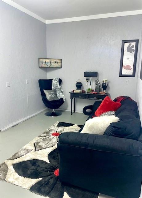 living area with ornamental molding and finished concrete floors