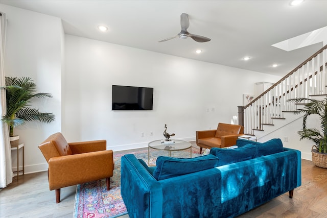 living room featuring ceiling fan, wood-type flooring, and a skylight