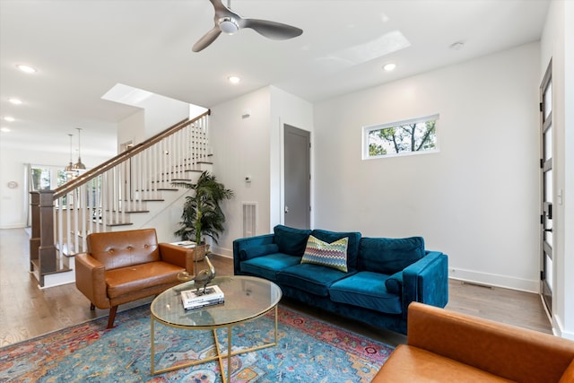 living room with hardwood / wood-style floors, ceiling fan, and a skylight