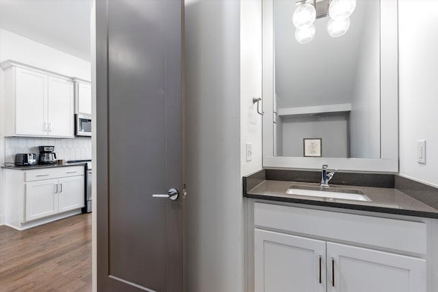 bathroom with vanity, tasteful backsplash, hardwood / wood-style flooring, and a notable chandelier