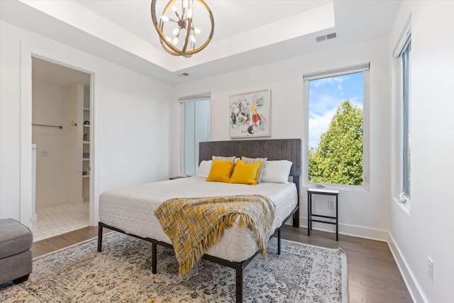 bedroom featuring multiple windows, hardwood / wood-style flooring, and a notable chandelier