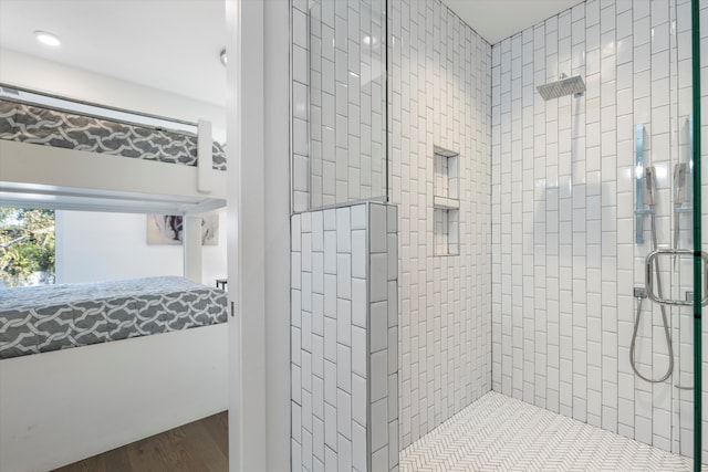 bathroom with tiled shower and hardwood / wood-style floors