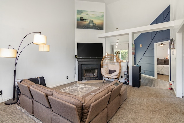 carpeted living room with ceiling fan and a towering ceiling