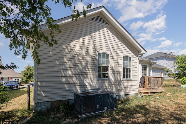 view of side of property with a yard, central AC unit, and a deck