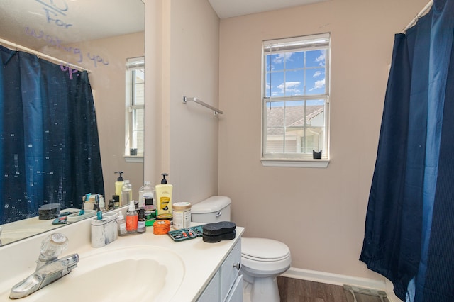 bathroom with a healthy amount of sunlight, wood-type flooring, toilet, and vanity