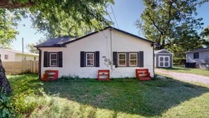 rear view of property featuring a lawn and a storage shed