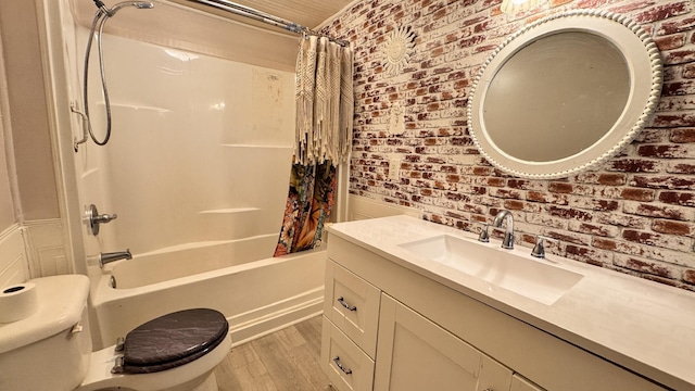 full bathroom with hardwood / wood-style floors, vanity, toilet, shower / bathtub combination with curtain, and brick wall