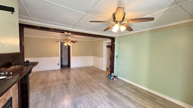 unfurnished living room featuring hardwood / wood-style flooring, ceiling fan, and crown molding