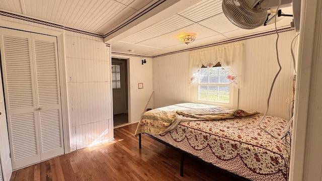 bedroom featuring wood-type flooring, ornamental molding, and a closet