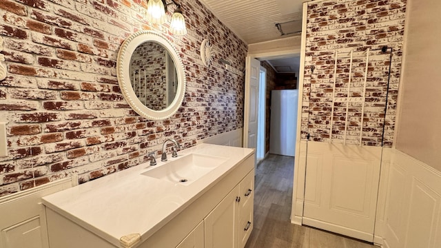 bathroom featuring vanity, hardwood / wood-style flooring, and brick wall