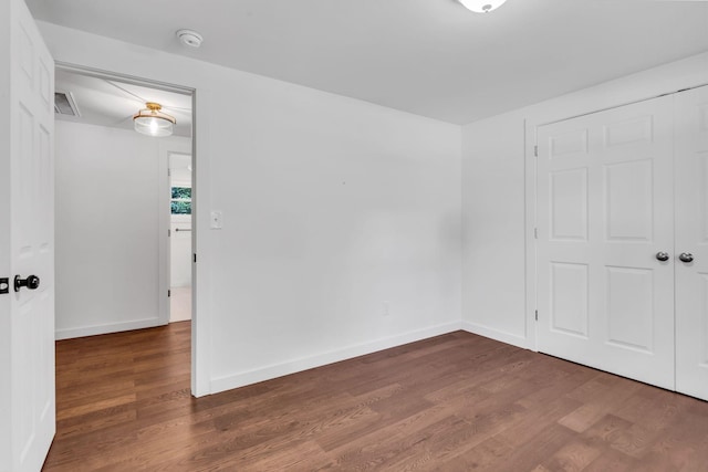 empty room with dark wood-type flooring, baseboards, and visible vents