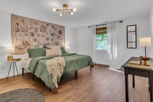 bedroom featuring a notable chandelier, wood finished floors, and baseboards