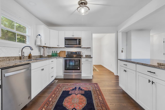 kitchen featuring dark wood-type flooring, stainless steel appliances, sink, decorative backsplash, and stone counters