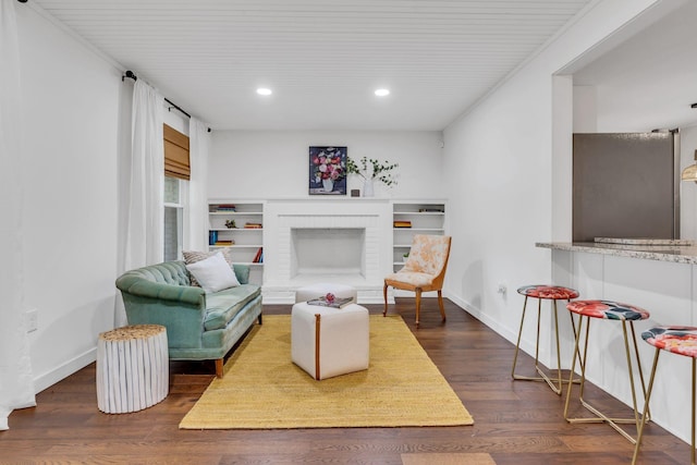 living area with recessed lighting, baseboards, a brick fireplace, and dark wood finished floors