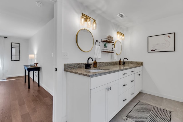 bathroom featuring a sink, visible vents, baseboards, and double vanity