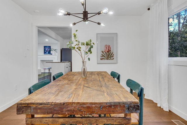 dining area with a chandelier, visible vents, baseboards, and wood finished floors