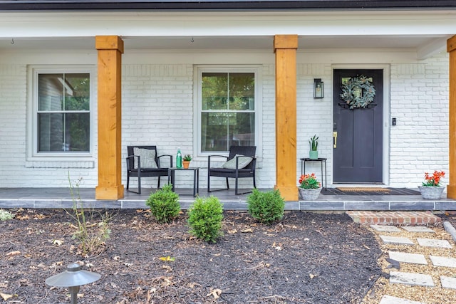 entrance to property with brick siding and a porch