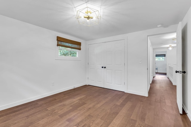 unfurnished bedroom featuring multiple windows, wood finished floors, and baseboards