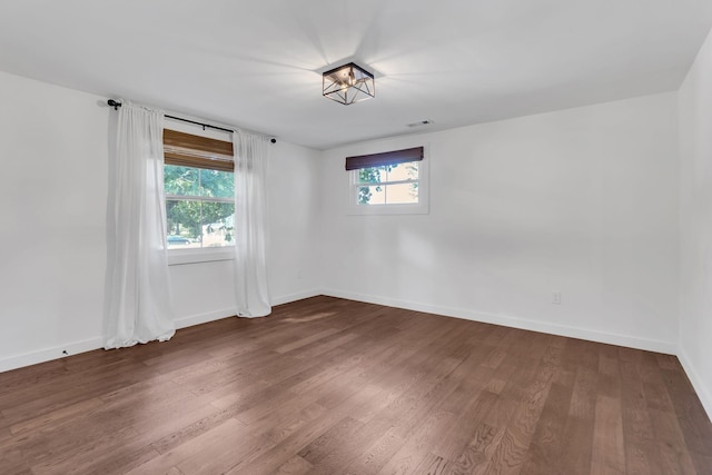 spare room with visible vents, baseboards, and wood finished floors