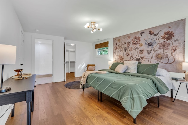 bedroom featuring light hardwood / wood-style flooring, a walk in closet, a chandelier, and a closet