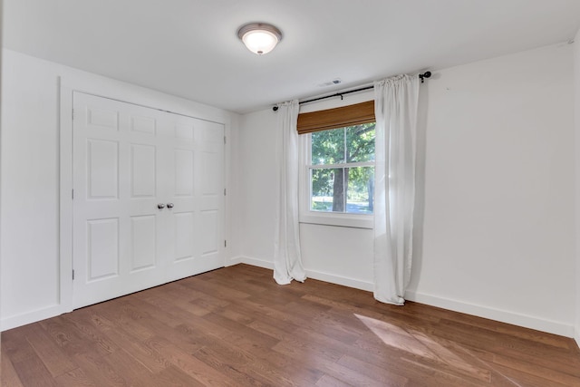 unfurnished bedroom with visible vents, baseboards, and wood finished floors