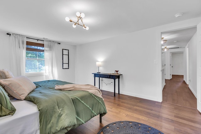 bedroom with wood finished floors, baseboards, and a chandelier