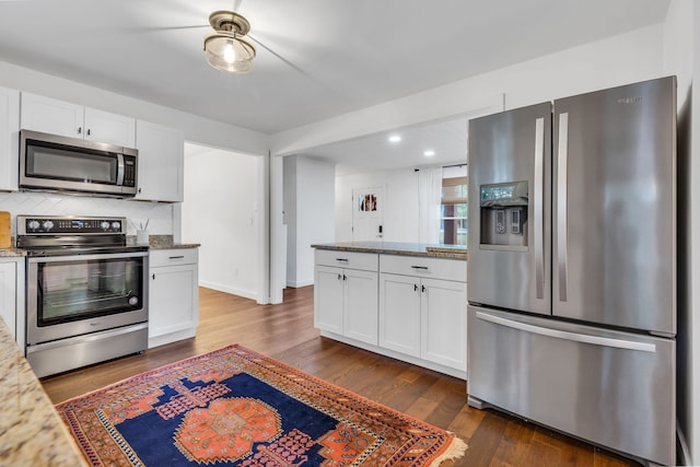 kitchen featuring dark wood-type flooring, light stone counters, and stainless steel appliances