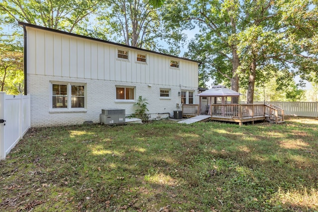 rear view of property with a wooden deck, a lawn, and central AC unit