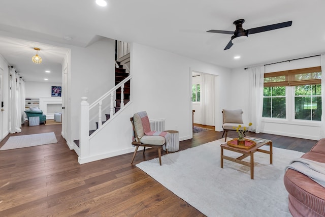 living room with a fireplace, dark wood-type flooring, a healthy amount of sunlight, and ceiling fan