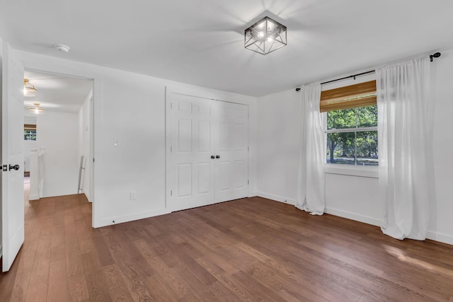 unfurnished bedroom with a closet, baseboards, and wood finished floors