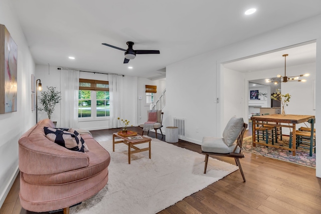 living room with ceiling fan with notable chandelier and wood-type flooring