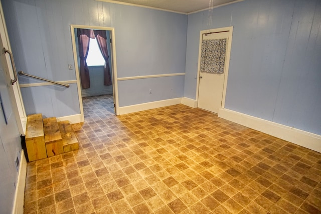 empty room with ornamental molding and wood walls