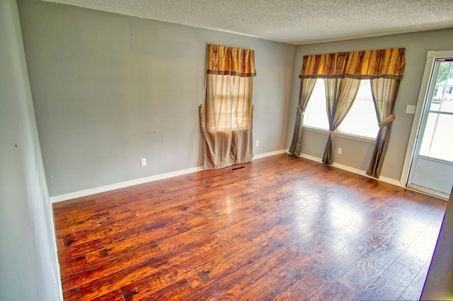 unfurnished room with wood-type flooring and a textured ceiling